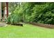 Lush backyard featuring a retaining wall and mature trees, creating a private outdoor space at 430 English Ivy Way, Woodstock, GA 30188