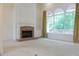 Open living room with a brick fireplace, large windows with curtains, and bright neutral colored carpet at 430 English Ivy Way, Woodstock, GA 30188
