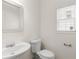 This half bathroom has a modern white sink and toilet, complemented by a decorative mirror at 795 Creek Glen Rd, Mableton, GA 30126