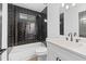 Modern bathroom with black tiled shower/tub and white vanity featuring quartz countertop at 4166 Riverhill Ne Ct, Roswell, GA 30075