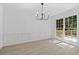 Elegant dining room featuring classic wall paneling, a modern chandelier, and abundant natural light at 4166 Riverhill Ne Ct, Roswell, GA 30075