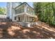 Back of the white house showing the multi-windowed sunroom and outdoor area at 4166 Riverhill Ne Ct, Roswell, GA 30075