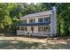 View of a two-story home with a welcoming front porch, set against a backdrop of mature trees at 4166 Riverhill Ne Ct, Roswell, GA 30075