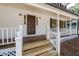 Close up of a classic front porch with white railings, wooden flooring, and a sturdy wooden front door at 4166 Riverhill Ne Ct, Roswell, GA 30075