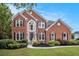 Beautiful two-story brick home with a well-manicured lawn, garden and mature landscaping at 2330 Springmonte Pl, Cumming, GA 30041