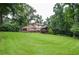 Large backyard with green grass and home and deck surrounded by mature trees at 4366 Cedar Wood Sw Dr, Lilburn, GA 30047