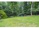 Beautiful backyard featuring a large grassy area, mature trees, and a charming wooden swing for relaxing at 4366 Cedar Wood Sw Dr, Lilburn, GA 30047