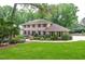 Traditional brick home featuring a manicured lawn, mature trees, and a meticulously maintained garden at 4366 Cedar Wood Sw Dr, Lilburn, GA 30047