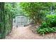 Backyard area with a wooden shed, landscaping, garden path, and mature trees at 4366 Cedar Wood Sw Dr, Lilburn, GA 30047