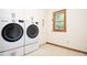 Bright laundry room with white front-load washer, dryer, and wooden window trim at 4366 Cedar Wood Sw Dr, Lilburn, GA 30047
