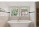 Bright bathroom featuring a freestanding tub, subway tile, and a view of mature trees at 1195 Cameron Ct, Atlanta, GA 30306