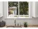 A sunny kitchen window offers a view of lush greenery and the exterior of the charming cottage at 1195 Cameron Ct, Atlanta, GA 30306