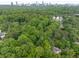 Aerial view of a secluded home surrounded by lush trees, with a city skyline visible in the distance at 306 Pinecrest Ne Rd, Atlanta, GA 30342