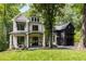 Elegant two-story home with stone accents, black trim, and attached garage amidst a wooded landscape at 306 Pinecrest Ne Rd, Atlanta, GA 30342