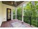 View of a covered patio with black metal railings overlooking a lush, green backyard and exterior door at 306 Pinecrest Ne Rd, Atlanta, GA 30342
