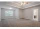 Large main bedroom with tray ceiling, plush carpet, and attached bathroom at 3469 Stoneleigh Walk, Lithonia, GA 30038