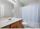 Bathroom featuring wood cabinets, white countertop, large mirror with lighting, and a toilet and bathtub with curtain at 4003 Maple Ridge Nw Ln, Acworth, GA 30101