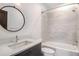 Bathroom with a single sink vanity, round mirror, and a tiled shower and tub at 1250 Oxley Nw Ln, Atlanta, GA 30307