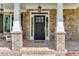 Inviting front entrance with a stylish black door, brick columns and stone accents at 3441 Shoreland Dr, Buford, GA 30518