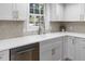 Close up of a kitchen sink featuring white countertops, modern faucet, stylish backsplash, and stainless steel dishwasher at 3981 Longview Dr, Chamblee, GA 30341