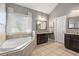 Bright bathroom with double vanity, soaking tub, and large window with blind coverings at 5075 Havenbrooke Ct, Cumming, GA 30040