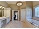 Bathroom features soaking tub with a tiled surround, heated towel rack, and large window at 10125 Brixton Pl, Suwanee, GA 30024
