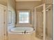 Bathroom featuring an enclosed shower and tub near a window with a unique design at 10125 Brixton Pl, Suwanee, GA 30024