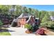 Exterior shot of a brick two-story home with three-car garage, manicured lawn, and mature trees at 10125 Brixton Pl, Suwanee, GA 30024