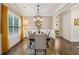 Bright dining room featuring a chandelier, wood floors, wainscoting and a large window with natural light at 4266 Suwanee Brook Ct, Buford, GA 30518