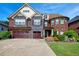 Elegant brick and stone home featuring a three-car garage, manicured lawn, and beautiful landscaping at 3642 Lake Estates Way Way, Atlanta, GA 30349
