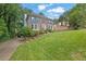 Charming two-story brick home featuring a well-manicured lawn, mature trees, and colorful flower beds at 3897 Tanbark Ct, Marietta, GA 30066
