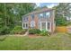 Charming two-story brick home featuring a well-manicured lawn, mature trees, and colorful flower beds at 3897 Tanbark Ct, Marietta, GA 30066
