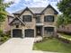 Charming two-story brick home with a well-manicured lawn and black trim and two-car garage at 570 Society St, Alpharetta, GA 30022