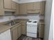 Compact kitchen featuring white appliances, light wood cabinets, and a stainless steel sink at 1993 Whitehall Forest Ct, Atlanta, GA 30316