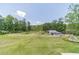 Expansive backyard featuring a lush lawn, mature trees, and a picturesque barn in the distance at 3040 Sandy Creek Ct, Loganville, GA 30052