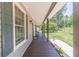 Inviting side porch with a wooden floor, stylish lighting, and a view of the lush green yard at 3040 Sandy Creek Ct, Loganville, GA 30052
