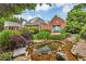 Exterior view of a charming home with a pristine pond, waterfall feature, professional landscaping and a muralled garage at 4119 Alayna Lee Cir, Mcdonough, GA 30252