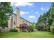 House exterior featuring an outdoor deck overlooking a vast, manicured backyard with mature trees at 6597 River Island Drive Dr, Buford, GA 30518