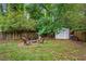 Secluded backyard featuring a fire pit with chairs and a storage shed, surrounded by mature trees and a wooden fence at 1564 Belva Ave, Decatur, GA 30032