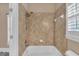 Neutral bathroom features a shower with tile surround and a white tub at 3451 Falls Branch Ct, Buford, GA 30519