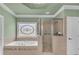 Elegant bathroom with a soaking tub, glass shower, and decorative stained glass window at 3451 Falls Branch Ct, Buford, GA 30519