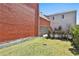 Green lawn with fence, bushes, and a brick building with a garage in the background at 175 Central Ave, Fayetteville, GA 30214