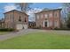 Elegant brick home featuring a circular driveway, manicured lawn, and a detached two-car garage at 4084 Peachtree Dunwoody Rd, Atlanta, GA 30342