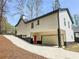 Side view of a home with white siding, black trim, and an attached garage on a sloping lot at 5728 Williams Rd, Norcross, GA 30093