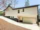 Side view of a home with white siding, black trim, and an attached garage on a sloping lot at 5728 Williams Rd, Norcross, GA 30093