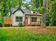 Cozy cottage-style home with a charming front porch nestled among lush green trees in the yard at 5728 Williams Rd, Norcross, GA 30093