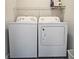 Clean laundry room with modern white washer and dryer units, plus overhead storage at 5728 Williams Rd, Norcross, GA 30093