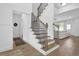 Bright foyer featuring hardwood floors, a staircase with black railings, and access to the living area at 145 Millennial Ct, Lawrenceville, GA 30045