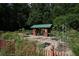 Scenic garden featuring a charming red shed with a green roof surrounded by plants and a wooded backdrop at 1174 City Park Ln, Decatur, GA 30033