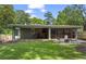 Exterior view of the backyard with a covered patio, grassy area, and mature trees, perfect for outdoor activities at 2180 Howell Mill Nw Rd, Atlanta, GA 30318